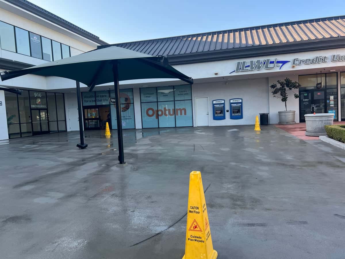Freshly pressure-washed plaza courtyard with shade umbrellas in front of a clinic and credit union
