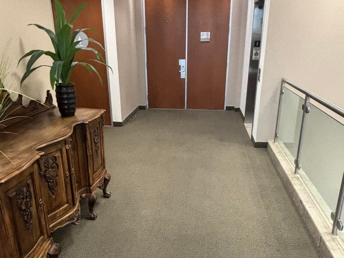Carpeted office-building corridor with elevator lobby and suite doors after Guardian janitorial service