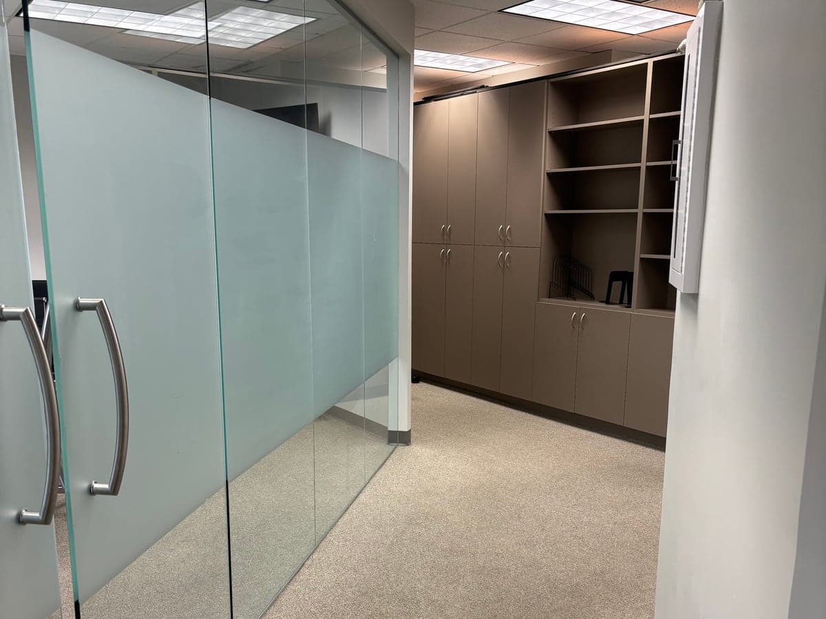 Office suite with frosted glass partitions, built-in cabinets, and freshly vacuumed carpet after Guardian office cleanup