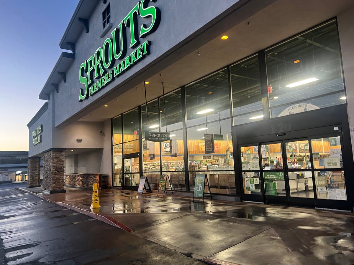 Freshly pressure-washed storefront entrance and sidewalk at a grocery-anchored Southern California shopping center at dawn