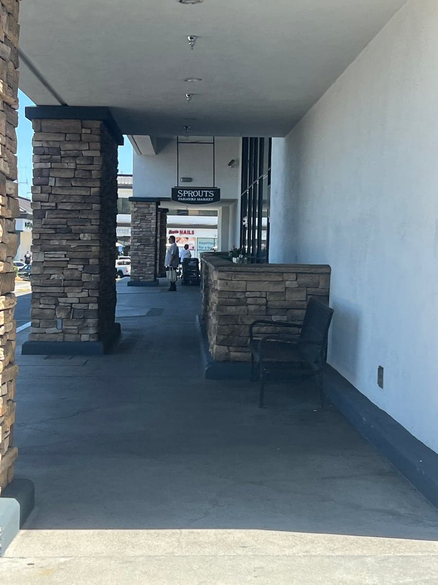 Covered retail walkway with stained, dull concrete before pressure washing